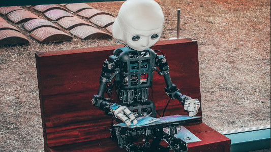 robot sitting on a bench reading a magazine